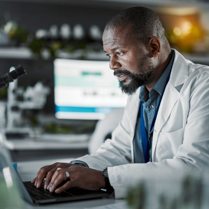 Scientist man, laptop and doing research in a laboratory with information technology and data analy